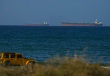 Iran Offers to Reopen Strait of Hormuz Within Days if Washington Agrees to Core Ceasefire Terms Large commercial oil tankers and cargo container ships navigating the narrow waters of the Strait of Hormuz.